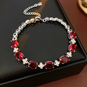 Macro shot of silver zircon flower bracelet with red oval stones on black leather box