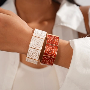 Close-up of geometric enamel elastic bracelets with vintage gold spiral texture patterns