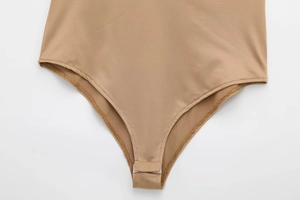 Détail de la fermeture à trois boutons-pression sur le body satiné couleur chair