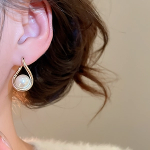 Gros plan de boucles d'oreilles élégantes en or et perles portées par un mannequin