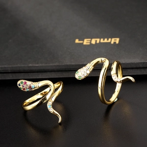 Macro shot of gold snake rings with colorful zircon inlay on a black textured backdrop