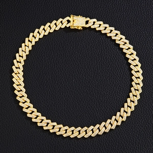 Detail of gold Cuban link necklace with pavé diamonds on textured black leather background
