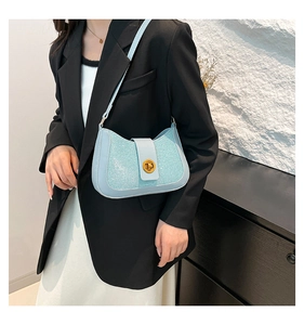 Detail of light blue shoulder bag featuring sequin panels and a gold twist lock closure