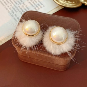 Close-up of winter faux pearl earrings featuring white plush fur and gold metal accents