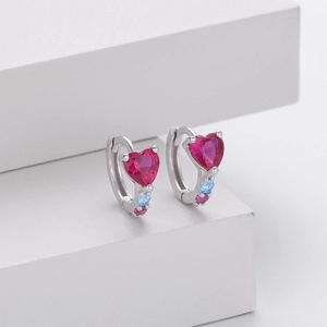 Detail of silver heart earrings featuring red ruby stone and colorful zircon accents