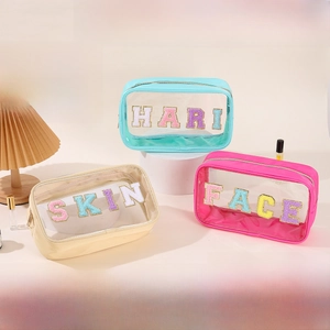 Detail of three transparent PVC toiletry bags with HAIR SKIN FACE chenille letter patches