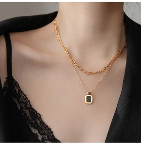 Detail of double-layer gold titanium necklace with figaro chain and black square pendant