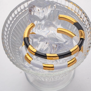 Detail of black and white enamel bamboo style gold bracelets displayed in an ice glass