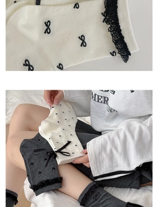 Detail of knit cotton socks featuring delicate black lace trim and bowknot accents