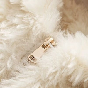 Macro detail of plush cream faux fur texture with premium light gold metal zipper