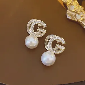 Elegant gold-plated pearl drop earrings featuring a sparkling zircon-studded G logo motif