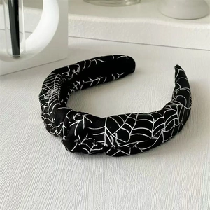 Détail du serre-tête en tissu noir avec motifs de toile d'araignée argentée et nœud central