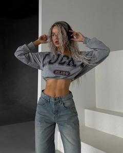 Gros plan sur un jean évasé bleu délavé à taille haute avec un sweat court gris LUCKY
