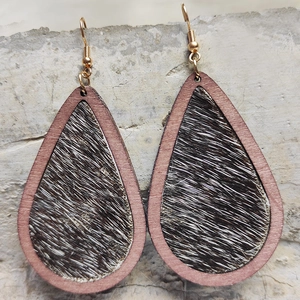 Macro view of teardrop wood earrings featuring black and white cow print calf hair texture