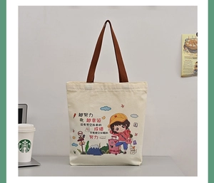 Detail of beige canvas tote bag with brown straps and motivational cartoon illustration