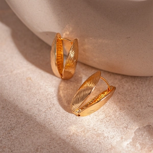 Macro shot of gold shell earrings with detailed textured patterns and clasp design