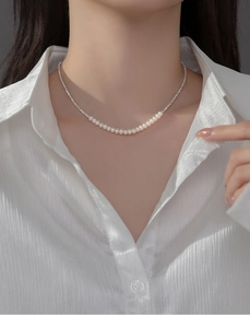 Detailed close-up of a French style S925 silver necklace with white pearls on a model