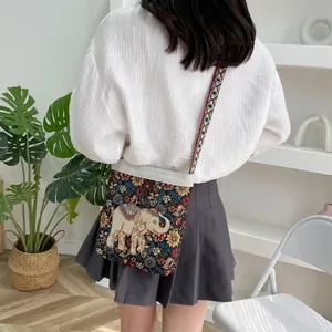 Detailed close-up of ethnic embroidered canvas bag with elephant floral patterns and strap