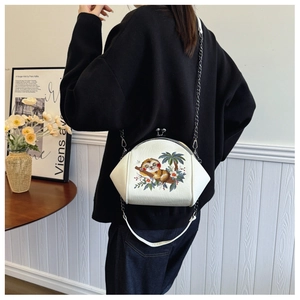 Detail of white embroidered shell crossbody bag with sloth pattern and silver chain strap
