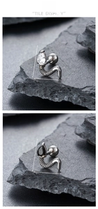 Macro detail of snake stud earring with teardrop zircon on stone textured background