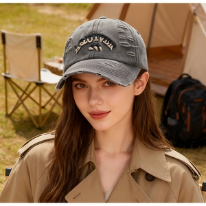 Close-up of vintage washed canvas baseball cap with embroidered ADVENTURE text and distressed detail