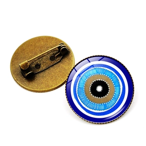 Detailed front and back view of a blue evil eye brooch with a bronze metal pin backing