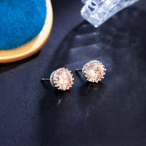 Macro shot of crown-shaped silver stud earrings featuring champagne zircon stones