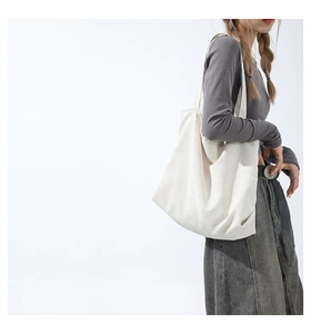 Side view of model carrying a large white corduroy tote bag with soft ribbed texture