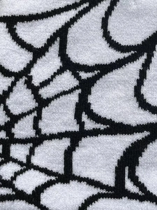 Close-up of high-density knit fabric and white spider web pattern on the black beanie
