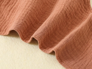 Close-up of soft reddish-brown double gauze muslin fabric texture with crinkle detail