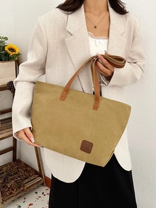 Olive green large canvas tote bag with brown straps styled with a chic beige suit