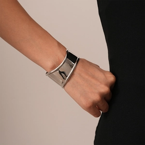 Close-up of polished silver wide cuff bracelet with geometric irregular design on wrist