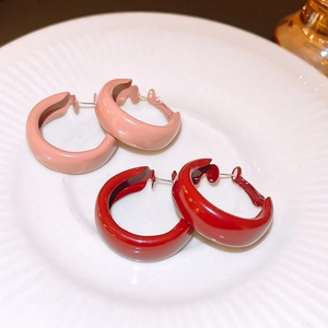 Retro geometric hoop earrings in pink and dark red enamel finish on a ceramic plate