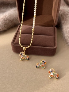 Close-up of gold-plated unicorn jewelry set with colorful stones and elegant pearls