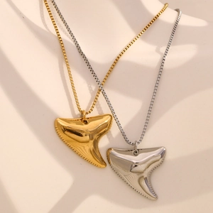 Close-up of shark tooth pendant necklaces in gold and silver finish with box chains