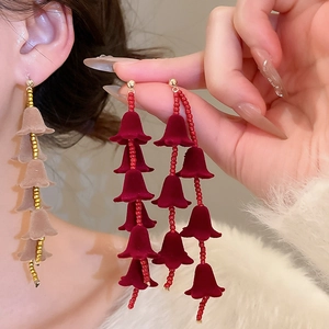Détail de boucles d'oreilles fleuries en flocage rouge et kaki à pampilles dorées