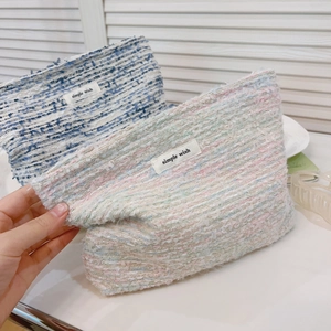 Close-up of tweed makeup bag showing blue and pink woven texture and zipper detail