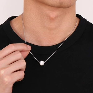 Collier minimaliste chaîne serpent argentée avec pendentif rond blanc porté par un homme