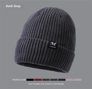 Macro detail of dark grey ribbed knit beanie with foldable brim and woven brand label