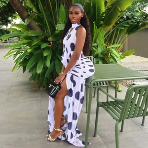 Polka dot halter neck dress with high side slit and open back design shown in lush outdoor setting