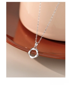 Macro view of S925 sterling silver Mobius ring necklace on a ceramic tray