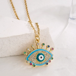 Golden Evil Eye pendant necklace with blue enamel and colorful zircons on white stone