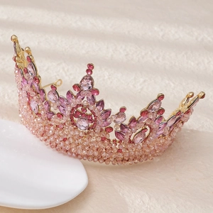 Detailed macro shot of luxury gold bridal tiara featuring pink crystals and teardrop gems