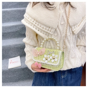 Detail of green tweed kids handbag with pearl handle, floral decor, and Love diamond lettering