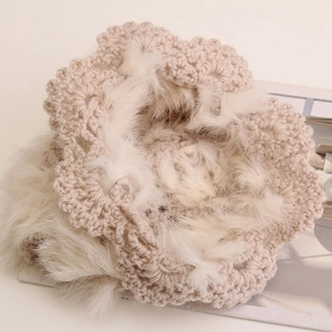 Detailed close-up of beige crochet knit beanie featuring fur trim and hollow floral patterns