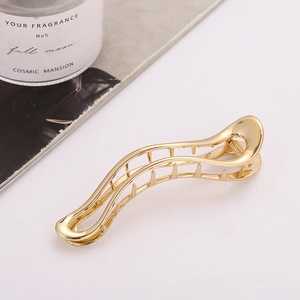 Detailed side view of a large golden metal hair claw clip with sleek streamlined design