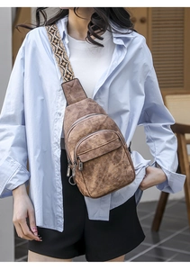 Detail of a brown PU leather chest bag featuring multiple zippers and a tribal strap