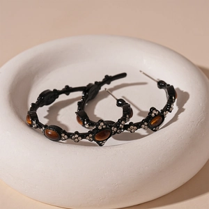 Macro detail of retro C-shaped earrings with amber gemstones and crystals on a pedestal