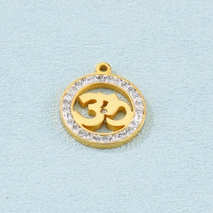 Detailed view of a gold Om pendant with clear crystals on a textured blue surface
