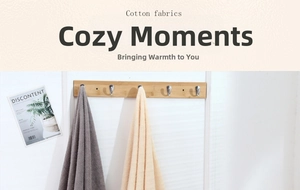 Detail view of thick cotton bath towels in dark grey and beige on wooden wall hooks